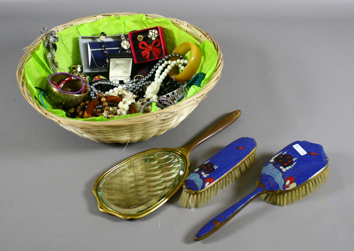 Assorted costume jewellery in wicker bowl along with enamelled back brush and mirror set.