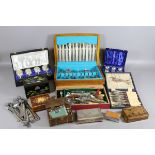 A collection of cased cutlery and goblets along with cigar and cigarette boxes and other