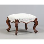 A Victorian walnut stool. With overstuffed seat and raised on carved scrolling supports, 60cm