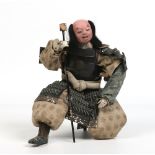 A Japanese carved and painted doll wearing embroidered costume and lacquered armour, 25cm. Condition