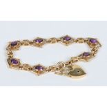 An 18 carat gold bracelet with heart shaped clasp and set with seven ovoid faceted amethysts.