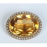 A Victorian yellow metal ovoid brooch set with a large faceted citrine under a border of seed