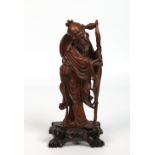 A Chinese carved hardwood figure of a fisherman. Holding a staff and raised on a pierced plinth,