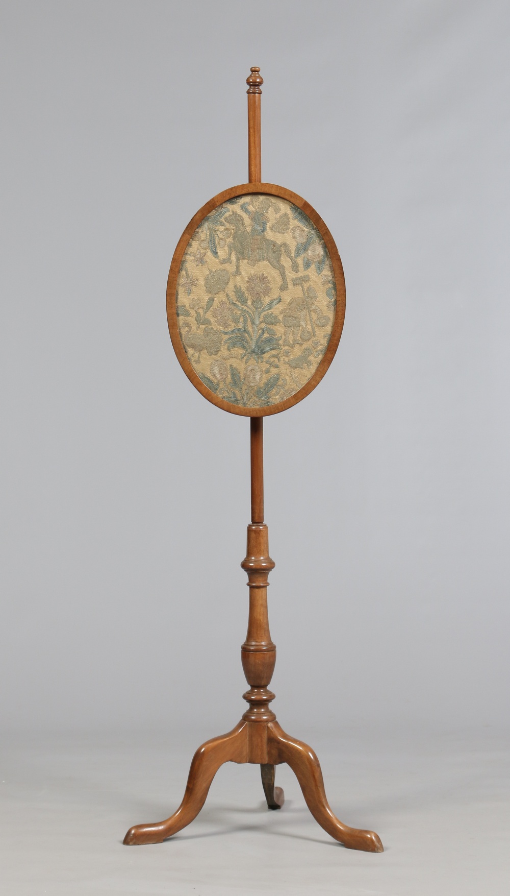 A Victorian mahogany oval pole screen raised on a tripod base and embroidered with flowers and