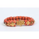 An Eastern coral and high carat gold bracelet. Formed from two rows of beads interspersed with
