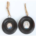 A pair of George III ivory portrait miniatures of a young girl and boy in carved oval frames.