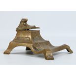 An Art Deco bronze desk stand with hinged cover incorporating an inkwell. Raised on bracket feet,