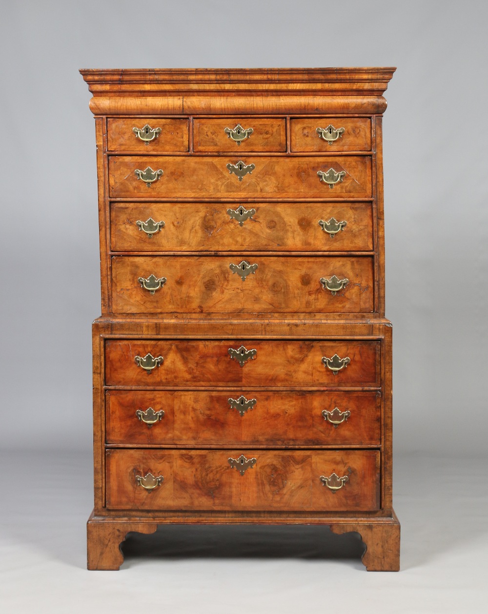 A Queen Anne figured walnut chest on chest. With concealed drawer to the moulded frieze,