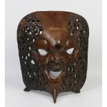 A large African carved hardwood mask of concave shape and with pierced sides formed as numerous