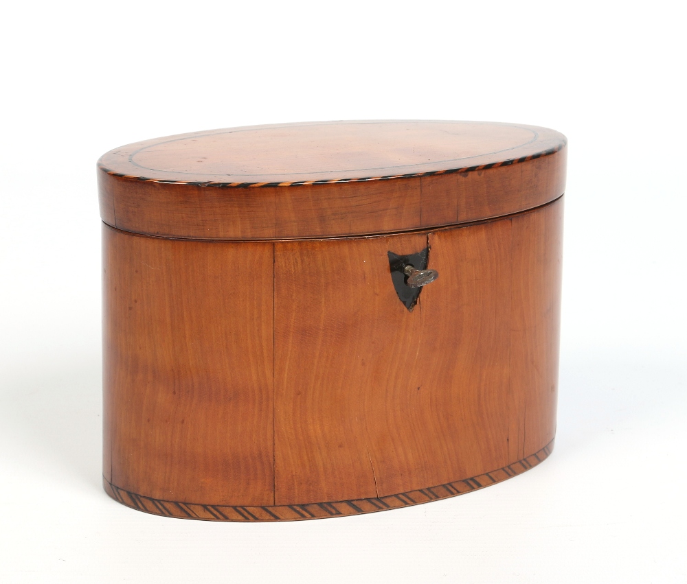 A Regency oval satinwood tea caddy. With cross hatched inlay, stringing and shield escutcheon,