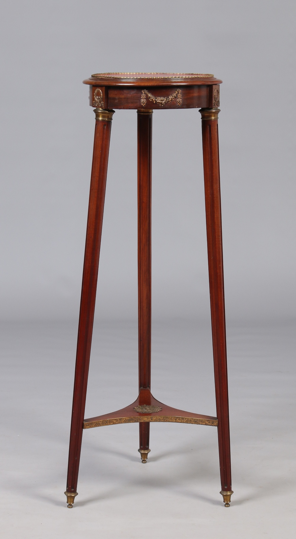 A Victorian mahogany leather topped torchere stand with gilt metal mounts and raised on splay reeded