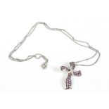 A 14 carat white gold stylized cross pendant set with pink sapphires and diamonds and supported on