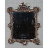 A Continental gilt framed wall mirror. With scrollwork frame adorned with shell motifs in the rococo