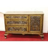 A oak sideboard ornamented with a carved Griffins raised on cabriole supports along with Draftmans