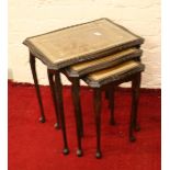 A nest of three carved mahogany and leather inset occasional tables.