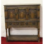 A Priory style carved oak court cupboard raised on turned supports.