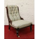 A Victorian carved mahogany and deep buttoned nursing chair raised on turned and reeded supports.