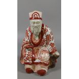 An early C20th Japanese figure formed as a seated elder holding a scroll decorated throughout with