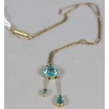 A yellow metal pendant on chain set with faceted blue stones.
