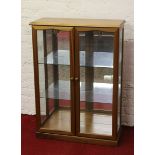 A light oak display cabinet with bevel edge glass.