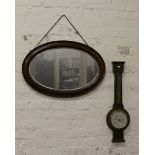 An oval mahogany bevel edge wall mirror and  oak cased anaroid barometer (AF).