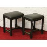 A pair of carved oak and leather topped stools.