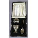 A cased silver christening set to include an egg cup, spoon and napkin ring,