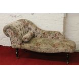 An upholstered chaise longue raised on turned supports.