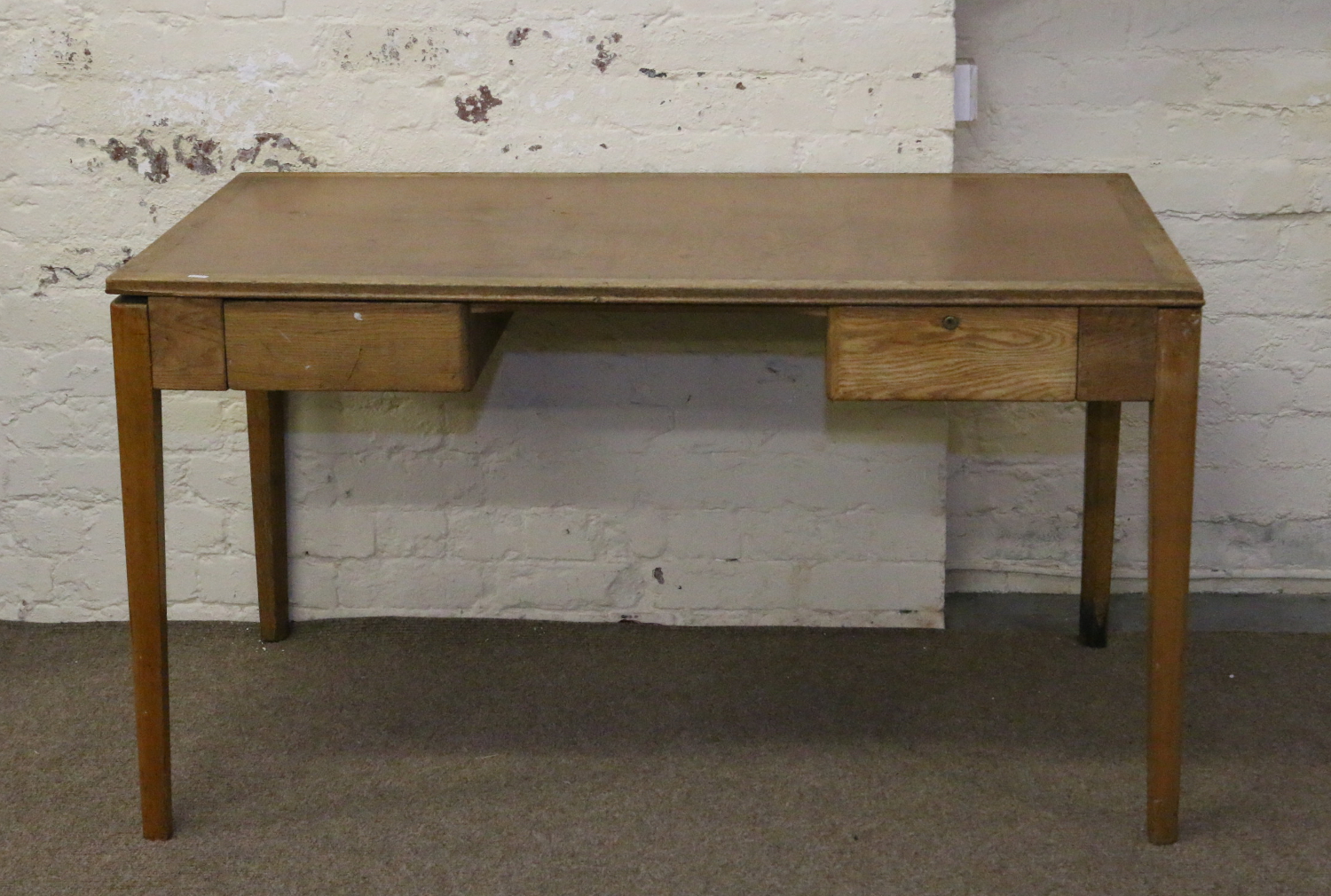 A 1950s light oak desk with inset top and raised on square tapering supports.