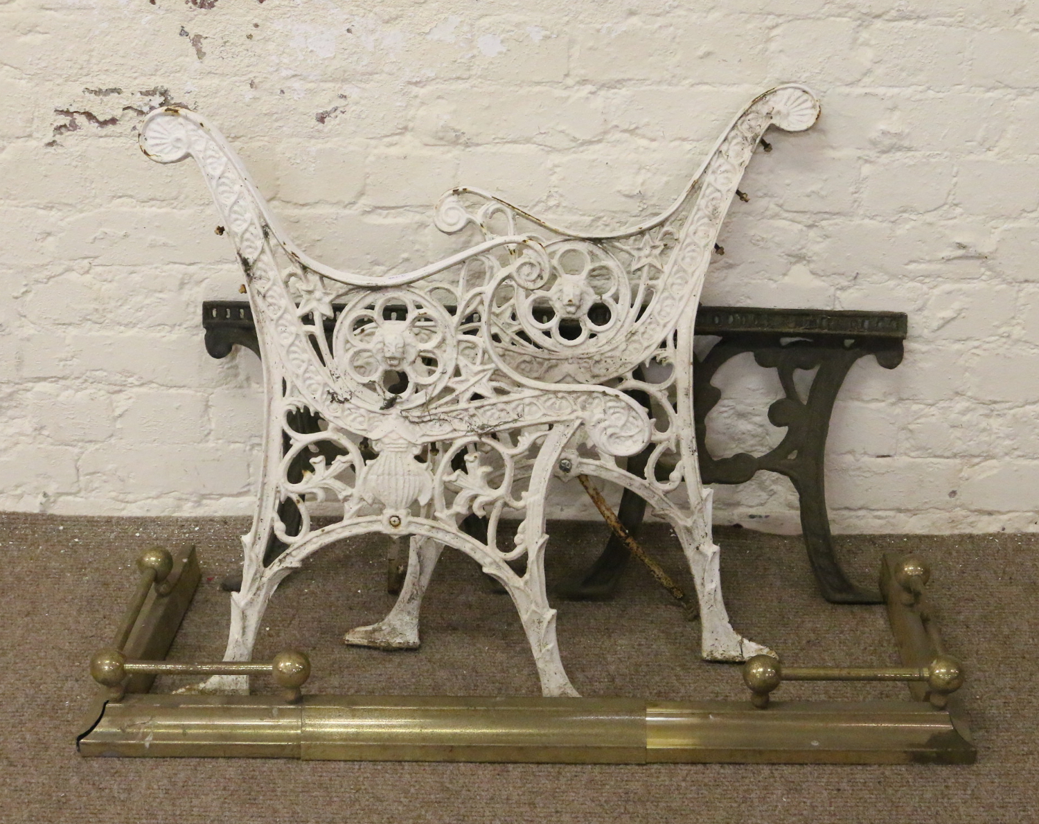 A brass fire fender along with a pair of cast iron bench ends and supports.