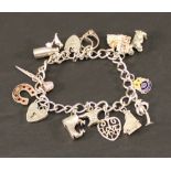 A SILVER AND WHITE METAL CHARM BRACELET of traditional form with various suspended charms, marked as