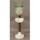 A 20TH CENTURY BRASS AND CERAMIC COLUMN OIL LAMP having a green tinted etched glass shade, brass