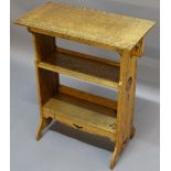 A SMALL LIBERTY STYLE OAK BOOKCASE, having a rectangular top, shaped and pierced brackets, two plain