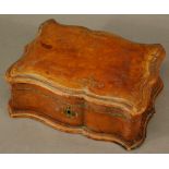 A TOOLED LEATHER COVERED JEWELLERY BOX of hinged serpentine rectangular form, with padded silk