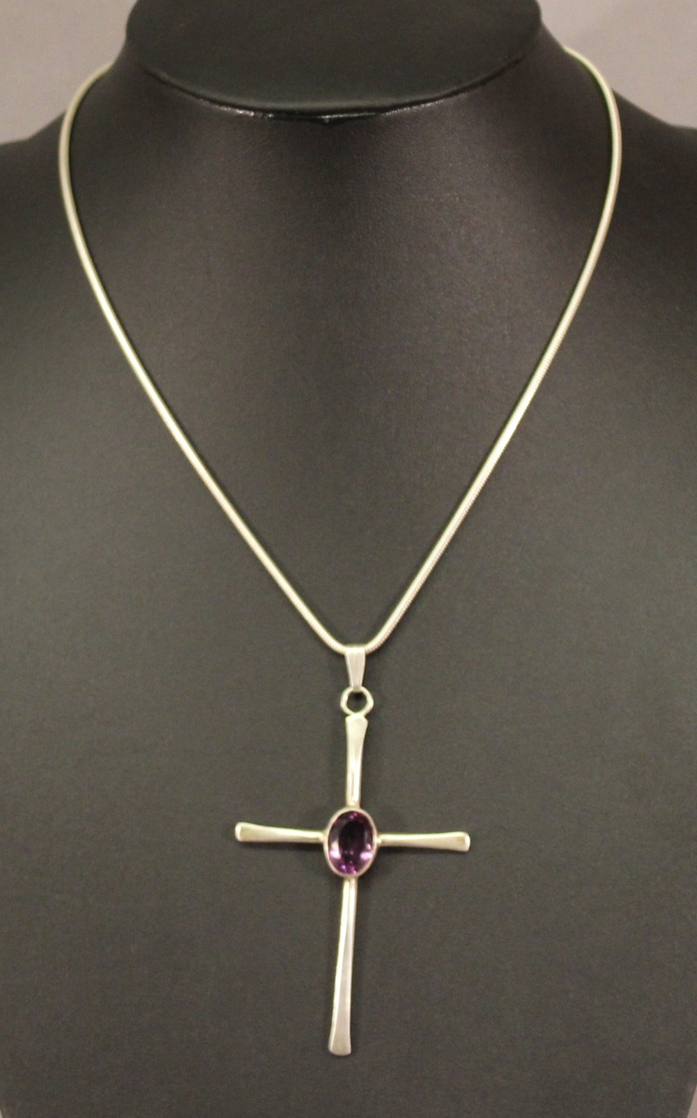 A SILVER AMETHYST SET CROSS PENDANT with central oval-cut amethyst, suspended by a multi-linked