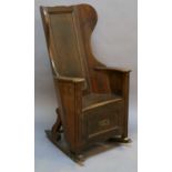 AN EARLY 19TH CENTURY PITCH PINE ROCKING LAMBING CHAIR having a panelled back with shaped