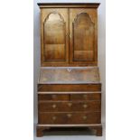 AN 18TH CENTURY WALNUT BUREAU BOOKCASE having a moulded cornice, two arched panel doors and candle