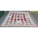 A VICTORIAN PATCHWORK COVERLET constructed with geometric designed panels in a floral border.  228cm