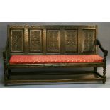A LATE 18TH CENTURY OAK SETTLE having an S-scroll carved frieze, five rectangular panels carved with