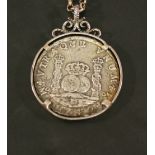 A 1742 EIGHT REALES (PIECE OF EIGHT) COIN MEDALLION, the coin set in a white metal surround engraved