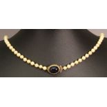 A PEARL NECKLACE, the string of pearls with 9ct gold clasp inset with oval glitter stone cabochon.