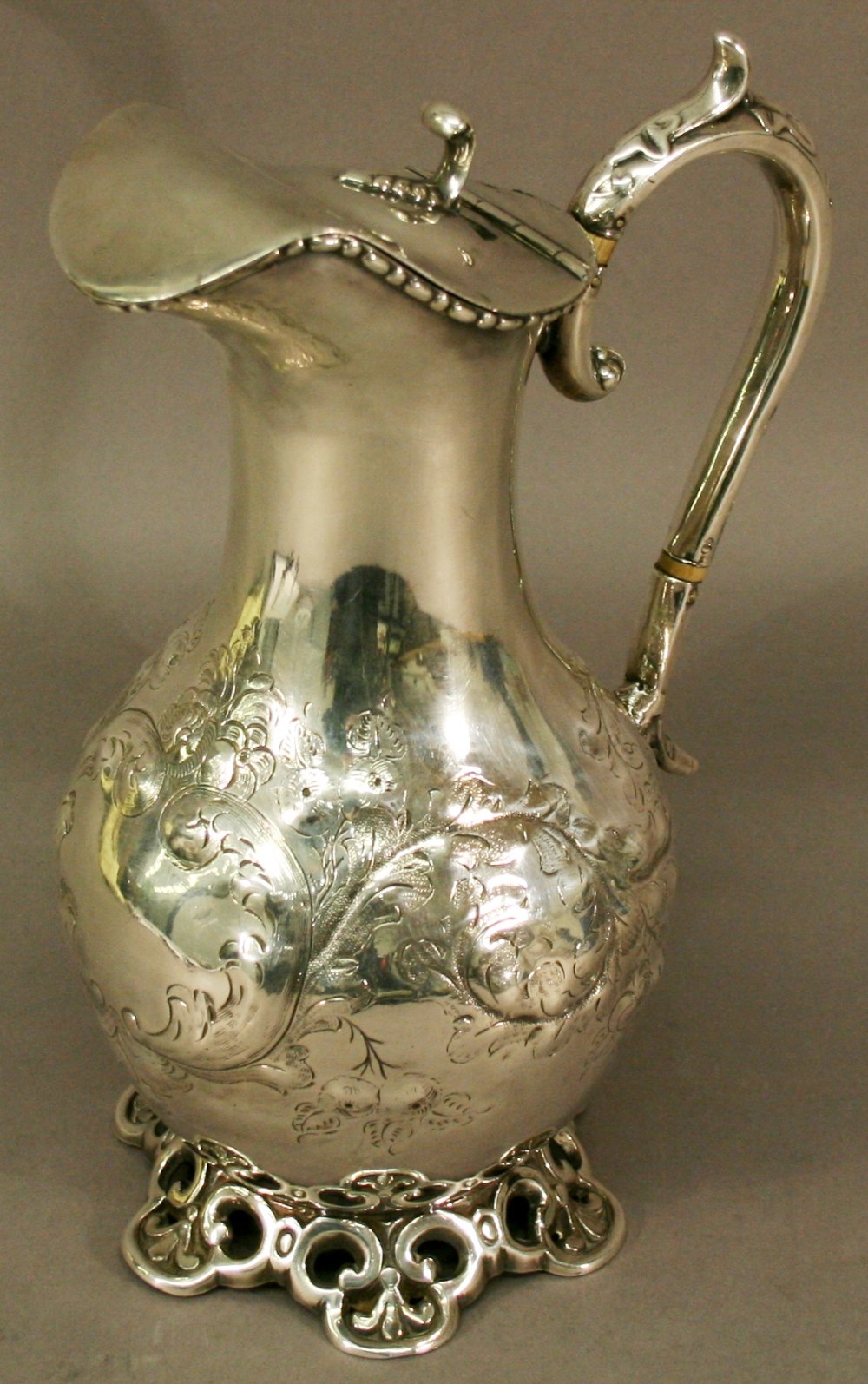 A 19TH CENTURY WHITE METAL HOT WATER JUG of baluster form with hinged cover and scroll handle with
