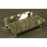 A SILVER PLATE ON BRASS TWO HANDLED DISH of rectangular form with crimped edge and foliate handles