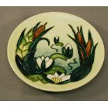 A MOORCROFT POTTERY 'LAMIA' PATTERN PLATE of small proportions, tube-lined with lily pads and reeds.