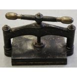 A VICTORIAN CAST IRON BOOK PRESS mottled black finish with gilt veining, the handles with brass