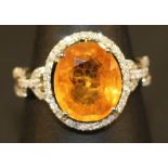 A 14K WHITE GOLD AND DIAMOND RING set with an oval yellow cut sapphire approx. 5.76ct, diamonds