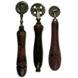 THREE 19TH CENTURY TREEN-HANDLED PASTRY JIGGERS each with a brass wheel and supports, 18.5cm, 13.