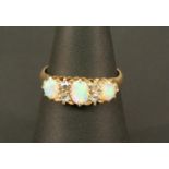 AN 18CT GOLD OPAL AND DIAMOND RING with three oval opal cabochones interspersed by small rose-cut