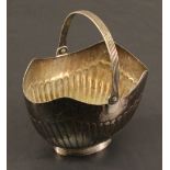 A LATE VICTORIAN SILVER SUGAR BASKET of oval form with shaped rim and reeded over handle, the body