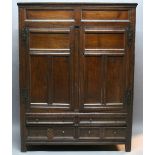 AN OAK WARDROBE having a moulded cornice, panelled frieze, two triple-panelled doors with iron H-